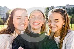 Close-up portrait, three girls schoolgirls teenagers, summer outdoors. Happy smiling play, Photography phone, selfie