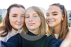 Close-up portrait, three girls schoolgirls teenagers, summer outdoors. Photography on phone, selfie photo, online app