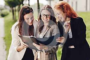 Close up portrait of three successful caucasian businesswomen in suits standing on the street