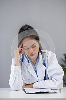 Close up portrait of tired female doctor sitting at the desktop and working on laptop in the office of modern clinic