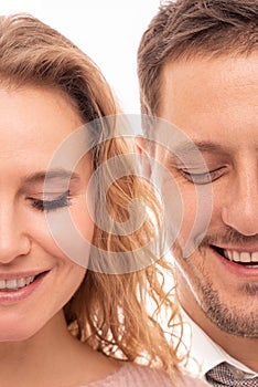 Close up portrait of two halves of face a positive smiling man and woman with closed eyes on white background.  Halfface