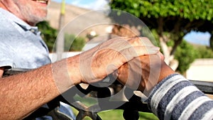 Close up and portrait of two hands shaking together and old and mature people talking sitting on a bench and having fun - taking c