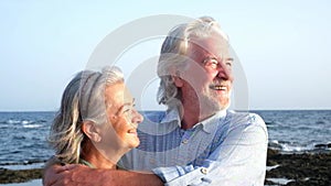 Close up and portrait of two happy and active seniors or pensioners having fun and enjoying looking at the sunset smiling with the
