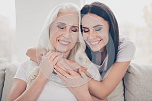 Close-up portrait of two nice attractive lovely cheerful dreamy sweet gentle women sitting on sofa granddaughter