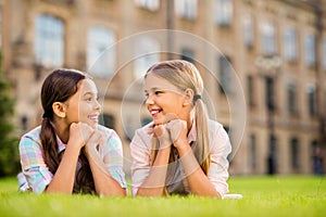 Close-up portrait of two nice attractive winsome lovely cute friendly cheerful cheery pre-teen girls lying in green