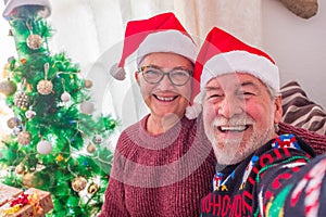 Close up and portrait of two pensioners and senior looking at the camera smiling and enjoying taking a selfie the christmas day at