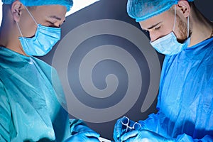 Close-up portrait of two surgeons operating in an operating room with instruments. In sterile medical surgical special clothing