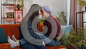 Close-up portrait of two young lesbian women family couple, girls embrace, hug each other at home