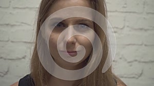 Close-up portrait of an unhappy young girl almost crying on a brick wall background. Upset with a sad face, feeling bad.