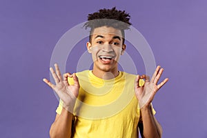 Close-up portrait of upbeat, relaxed young hipster guy with dreads assuring all good, everything be okay, show OK