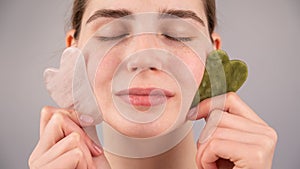 Close-up portrait of a woman with closed eyes holding two gouache scrapers near her face.