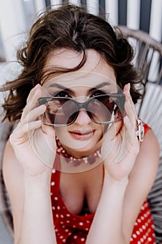 Close-up portrait of a woman with glasses. Photo of a fashionable girl with beautiful brown hair smiling at the camera.