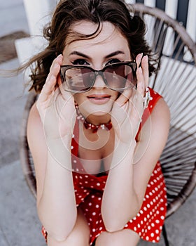 Close-up portrait of a woman with glasses. Photo of a fashionable girl with beautiful brown hair smiling at the camera.