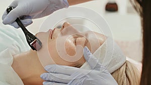 Close-up portrait of woman having beauty skin treatment. Therapist preparing skin with derma roller. photo