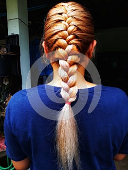 Close-up portrait of a woman& x27;s back, braid, beautiful hair, golden hair, fashion, braiding with professional hairdressers