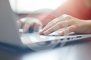 Close-up portrait of woman`s hands typing on laptop sitting at the table. Female businesswoman working on-line via laptop computer