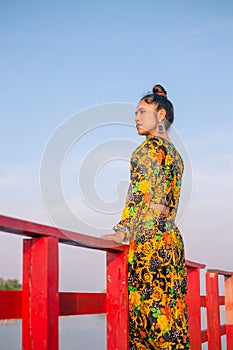 Close up portrait of a woman standing leaning on a wooden bridge