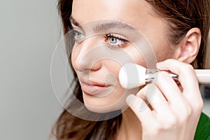 Close up portrait of a woman using makeup brush