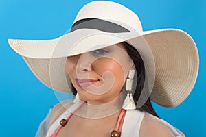 Close-up portrait of woman wearing beach hat and handmade earrings.