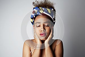 Close-up portrait of Young african girl with Afro curly hairstyle, posing aside with closed eyes, isolated over bright