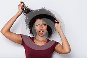 Close up young african woman pulling bad curly hair and looking worried photo