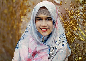Close up portrait of young Asian muslim woman face with golden leaves backdrop sheet