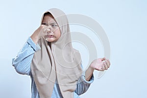 Close-up portrait of young asian woman holding nose closed because of bad smell