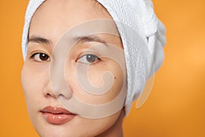 Close-up portrait of young Asian woman with perfect health skin of face. Isolated on orange background