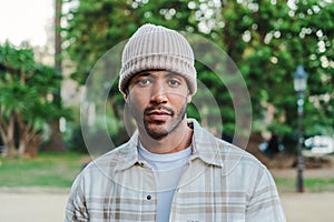 Close up portrait of young attractive african american man with beanie hat looking serious at camera. Front view of a