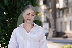 A close-up portrait of a young and attractive Caucasian woman in casual clothes while walking around the city. The concept of