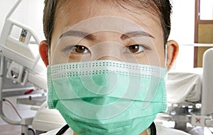 Close up portrait of young attractive and confident Asian Chinese medicine doctor woman in protective face mask and scrubs with