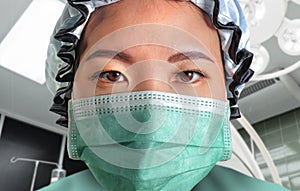 Close up portrait of young attractive and confident Asian Korean medicine doctor woman in protective head cap face mask and scrubs