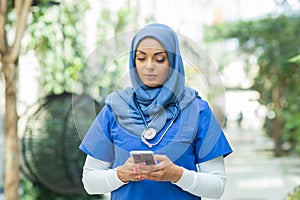 Close-up portrait of young and attractive muslim woman nurse in hijab. Middle Eastern female doctor outdoor on the