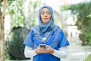 Close-up portrait of young and attractive muslim woman nurse in hijab. Middle Eastern female doctor outdoor on the