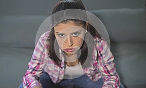 Close up portrait of young attractive and sad hispanic woman sitting at home couch looking stressed and worried in domestic proble