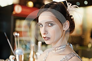 Close-up portrait of a young attractive woman in a 1920s style at the bar. Model with a beautiful make-up