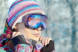 Close-up portrait of young attractive woman in bright sportswear and sport ski glasses for snowboarding and winter sport.
