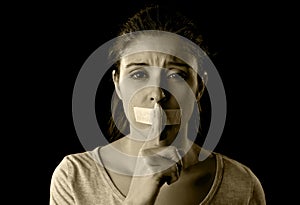Close up portrait of young attractive woman with mouth and lips sealed in adhesive tape restrained