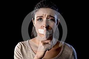 Close up portrait of young attractive woman with mouth and lips sealed in adhesive tape restrained photo