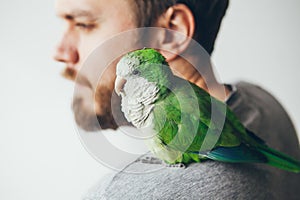 Close-up portrait of young beard man with his pet Quaker parrot