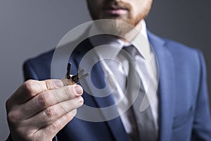 Close-up portrait of a young bearded guy of twenty-five years old, in a business suit, holding keys in his hand. On a gray