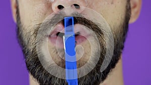 Close up portrait of a young bearded guy who pinches his lips with a clothespin.