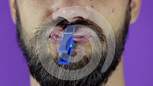 Close up portrait of a young bearded guy who pinches his lips with a clothespin.