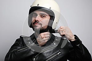 Close-up portrait of young bearded happy biker man with white cafe-racer helmet. White background.