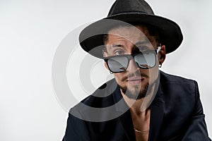 Close up portrait of young bearded serious man in black suit and hat isaolated over white background