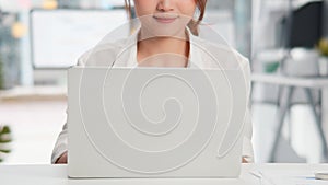 Close-up portrait of young beautiful Asian woman smiling, using laptop computer in home office. Happy work life