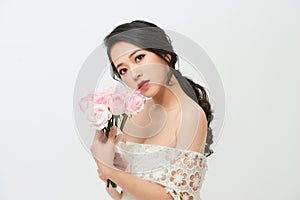Close-up portrait of young beautiful bride with stylish make-up and hairdo holding bouquet