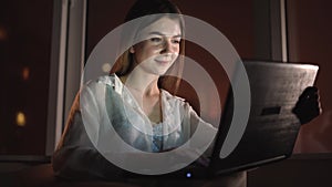 Close-up portrait of a young beautiful caucasian lady sitting at home alone at night near a large window. Night life. Is