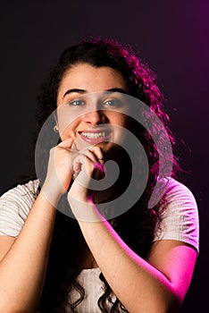 Close-up portrait of young beautiful cheerful woman with both hands on chin