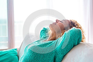 Close up and portrait of young beautiful curly woman relaxing and sleeping on the sofa or couch at home - vacations and free time